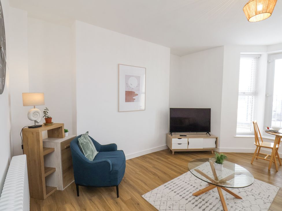 A living room with a tv, armchair, and dining area at Apartment 2 in Redcar