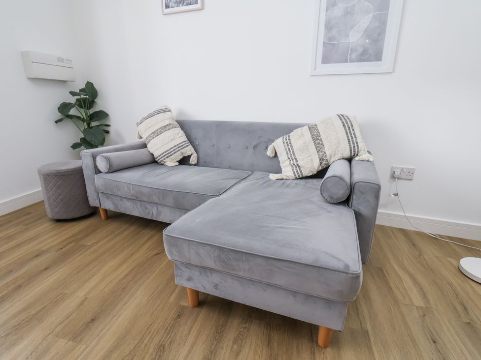 A sofa with cushions and a plant in a living room at Apartment 2 Redcar
