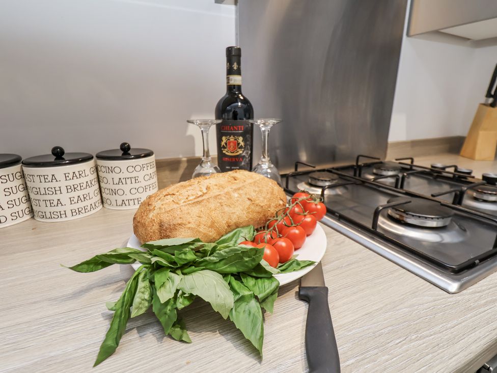A kitchen with bread, tomatoes, basil, wine and glasses at Apartment 2 in Redcar