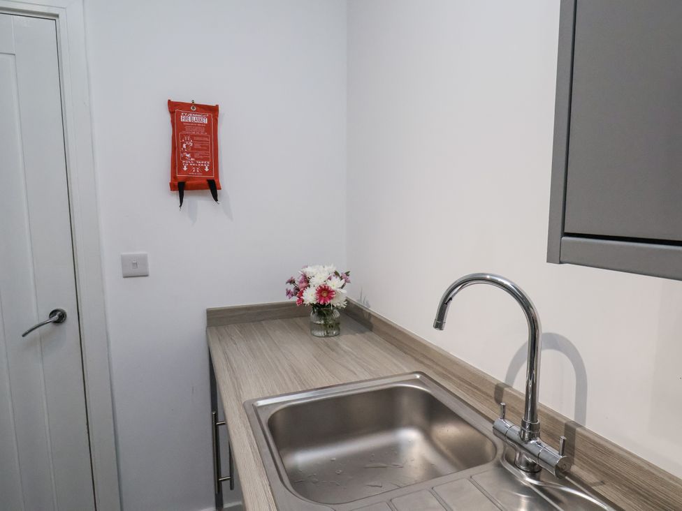 A kitchen with a sink, tap, and a vase with flowers at Apartment 2 in Redcar