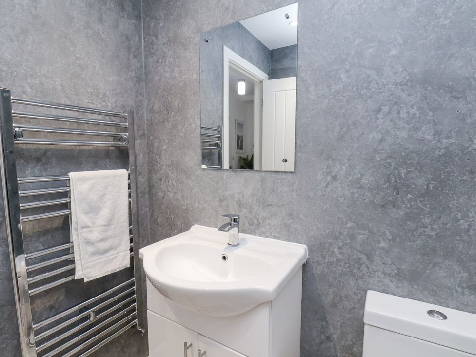 A bathroom with a sink, mirror, and towel rack at Apartment 2 in Redcar