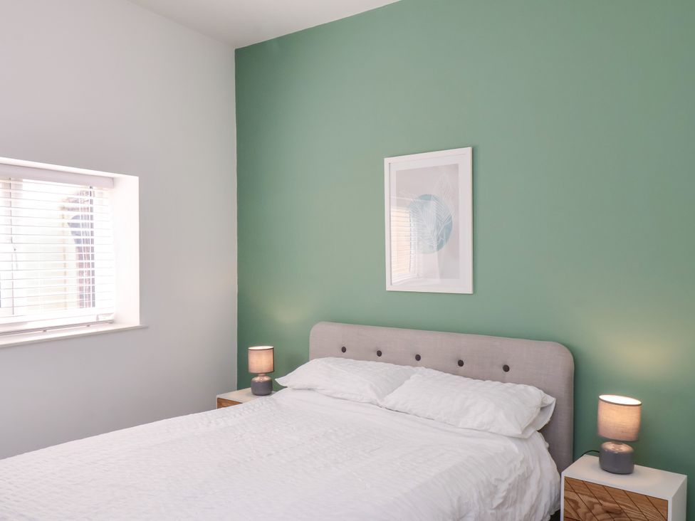 A bedroom with a bed, nightstands, and wall art at Apartment 1 ( 2 bed ) in Redcar