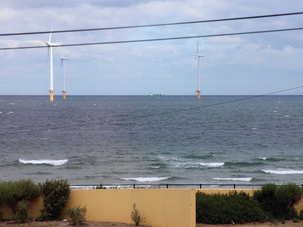 A view of wind turbines and a ship in the ocean at Glenholme Apartment 1 Redcar