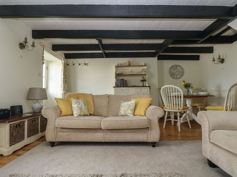 A living room with a sofa and dining area at Driftwood Cottage in St. Austell