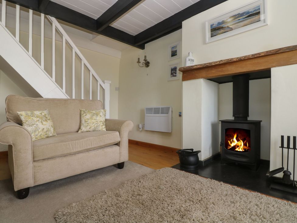 A living room with a sofa and fireplace at Driftwood Cottage in St. Austell