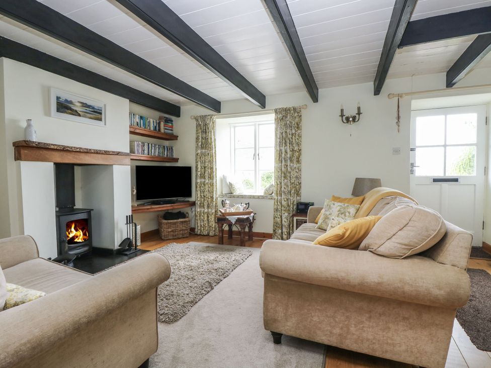 A living room with a fireplace and television at Driftwood Cottage in St. Austell
