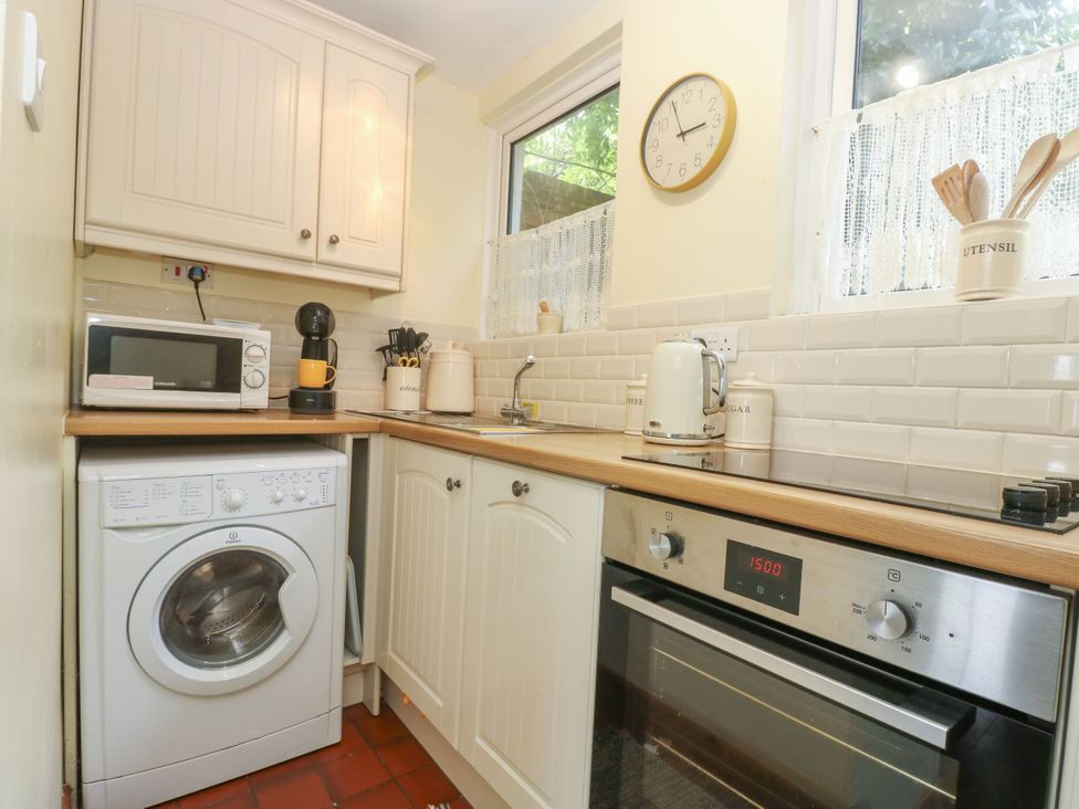 A kitchen with a washing machine and microwave at Driftwood Cottage in St. Austell