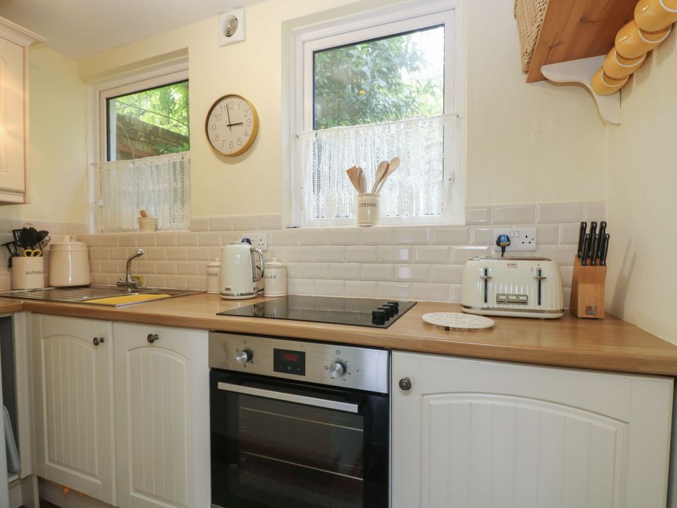 A kitchen with a sink, kettle, and toaster at Driftwood Cottage in St. Austell