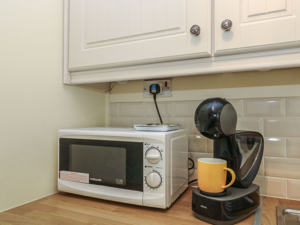 A kitchen with a microwave and coffee maker at Driftwood Cottage in St. Austell