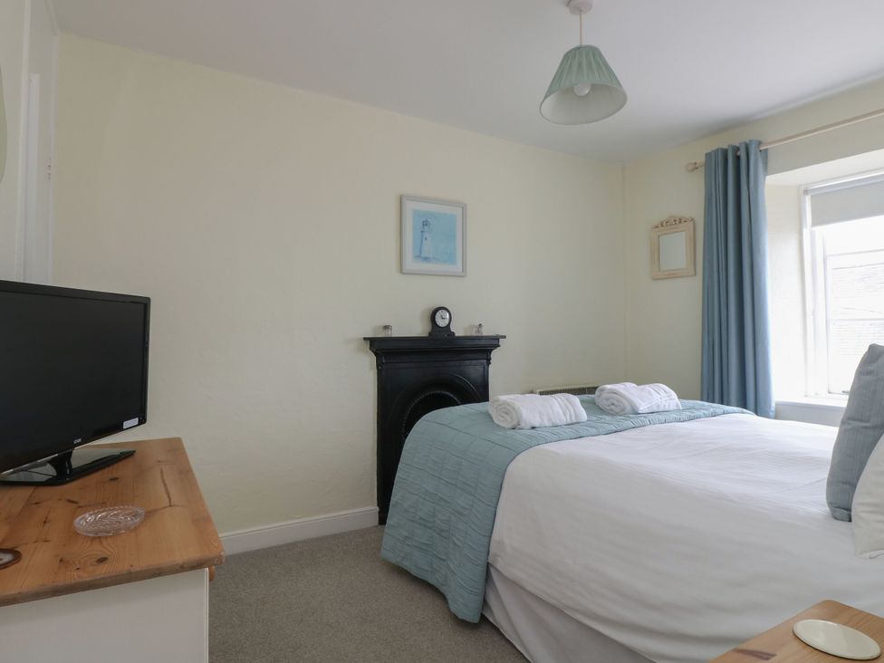 A bedroom with a bed and television at Driftwood Cottage in St. Austell