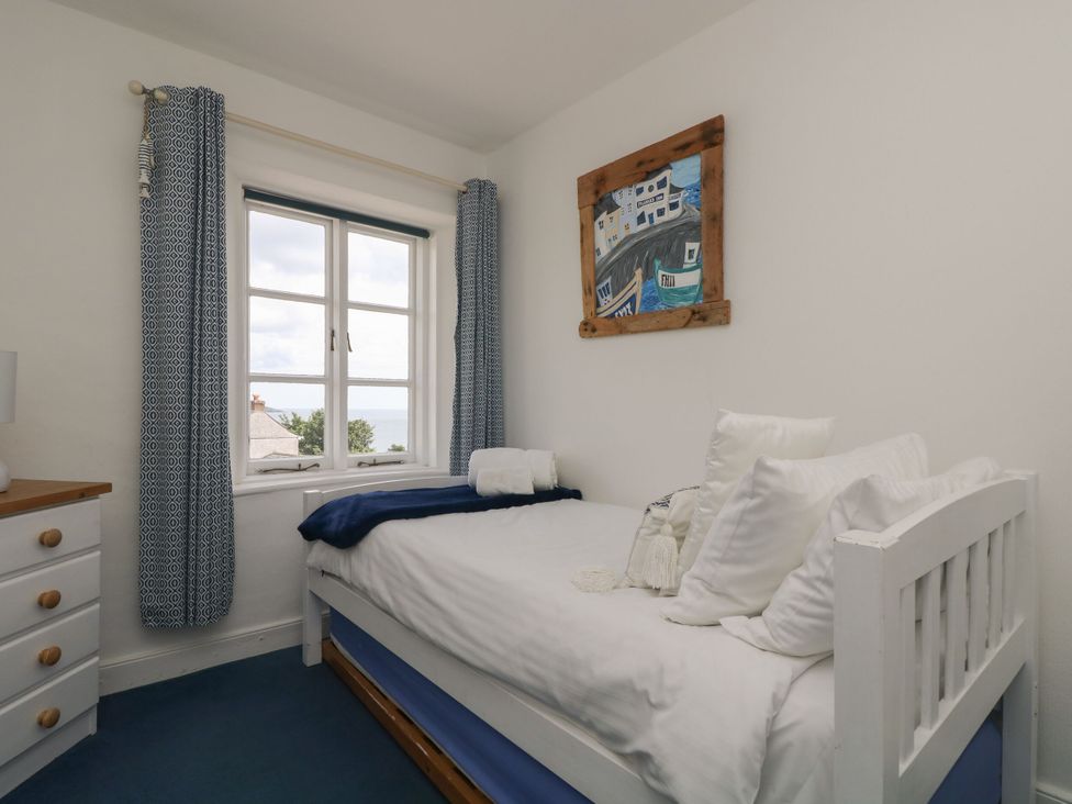 A bedroom with a bed and window at Driftwood Cottage in St. Austell