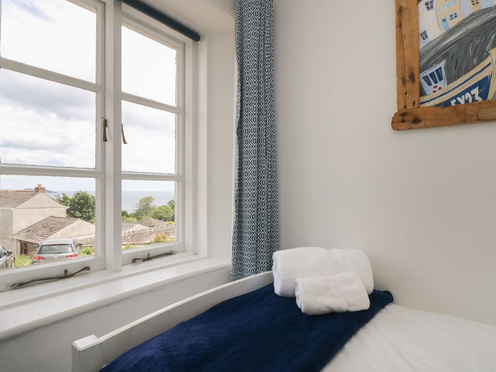 A bedroom with a window and towels on a bed at Driftwood Cottage in St. Austell