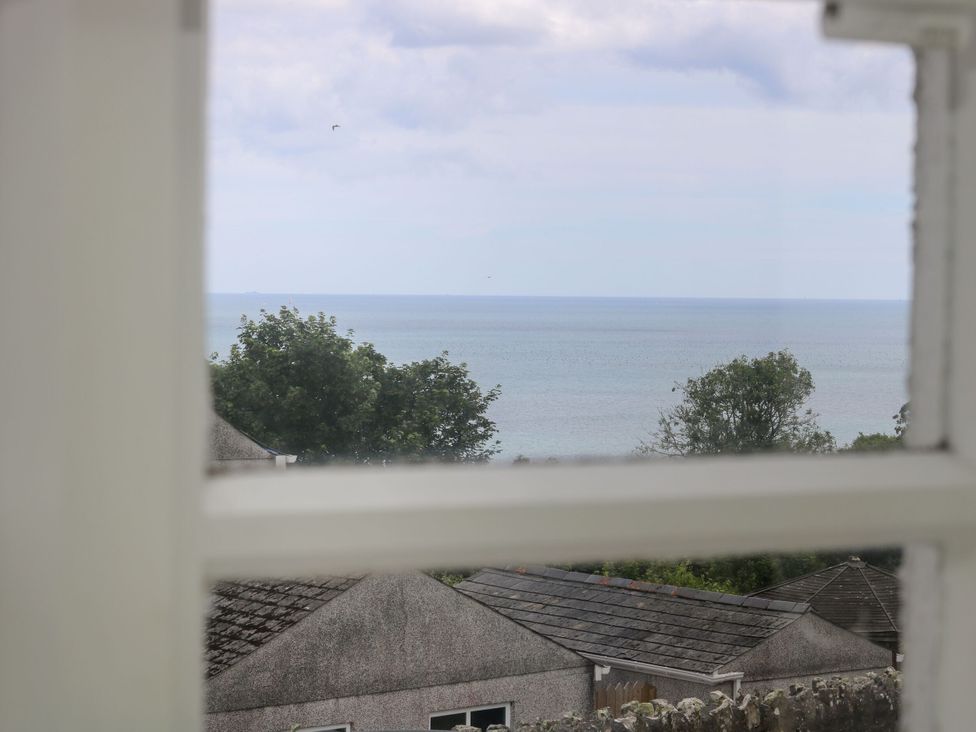 A view of the sea and trees through a window at Driftwood Cottage in St. Austell