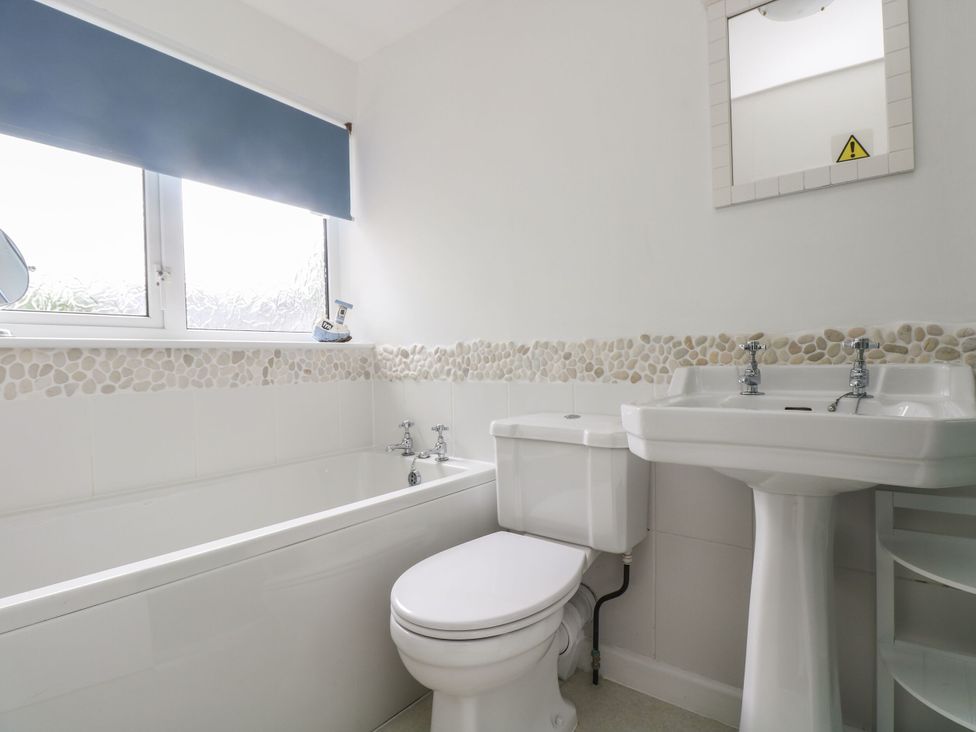 A bathroom with a bathtub, toilet, and sink at Driftwood Cottage in St. Austell