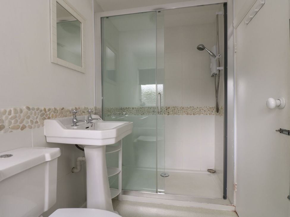 A bathroom with a shower and sink at Driftwood Cottage in St. Austell