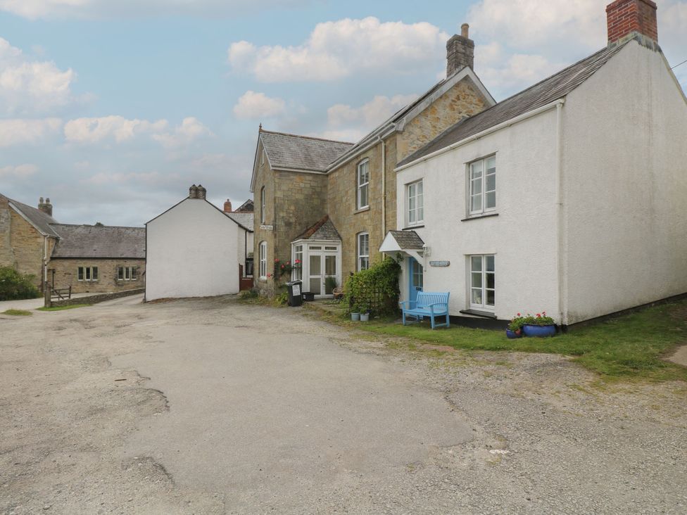 A house with a blue bench and a gravel pathway at Driftwood Cottage in St. Austell