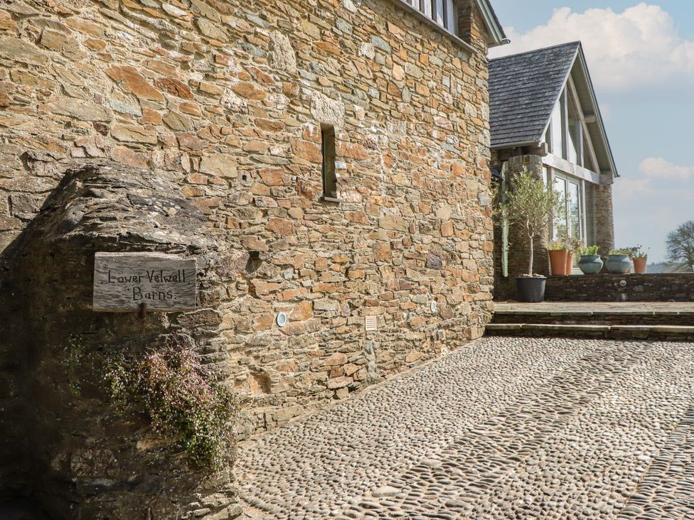 An outdoor area with a stone wall and a sign at Lower Velwell Barn in Totnes