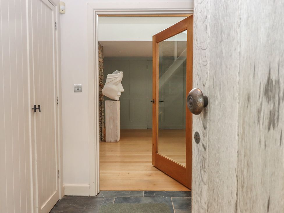 An entrance hall with a sculpture and mirror at Lower Velwell Barn in Totnes