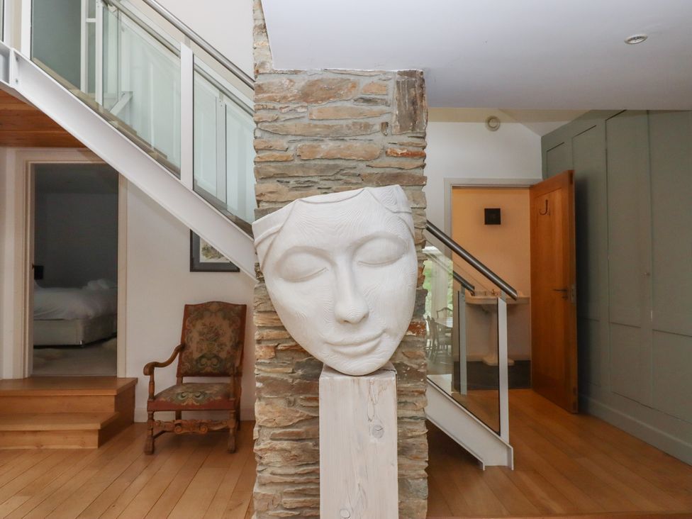 A hallway with a sculpture and staircase at Lower Velwell Barn in Totnes