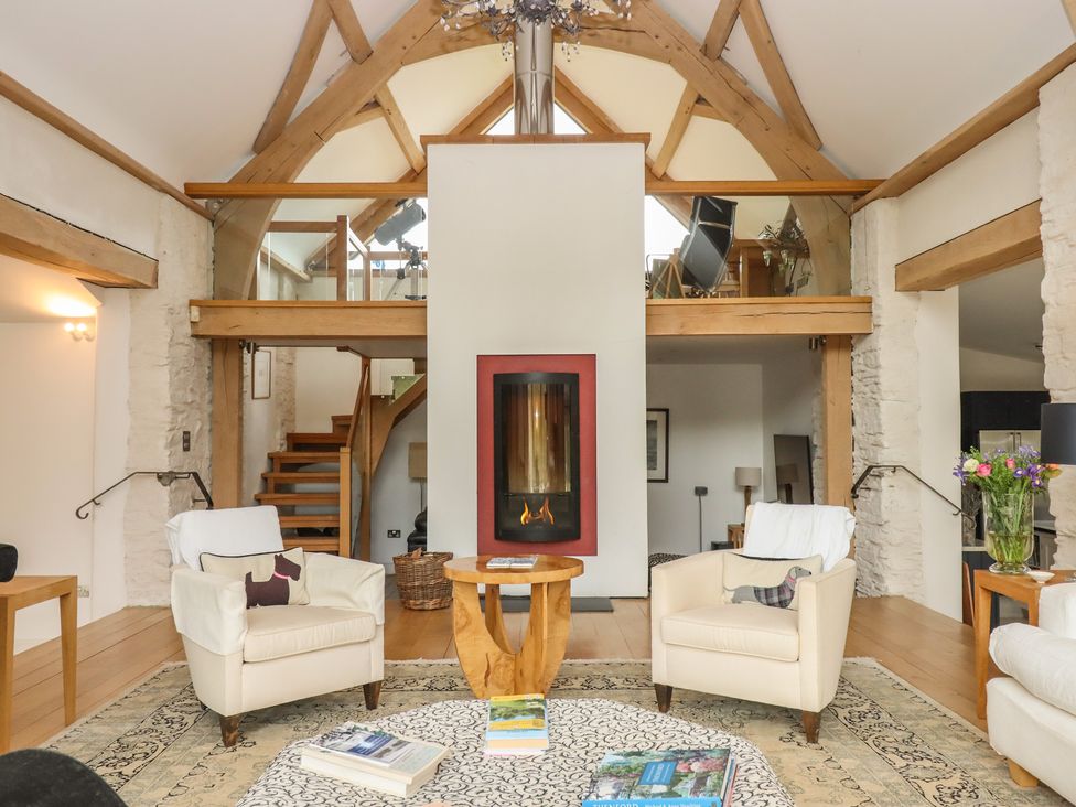 A living room with a fireplace and seating area at Lower Velwell Barn in Totnes