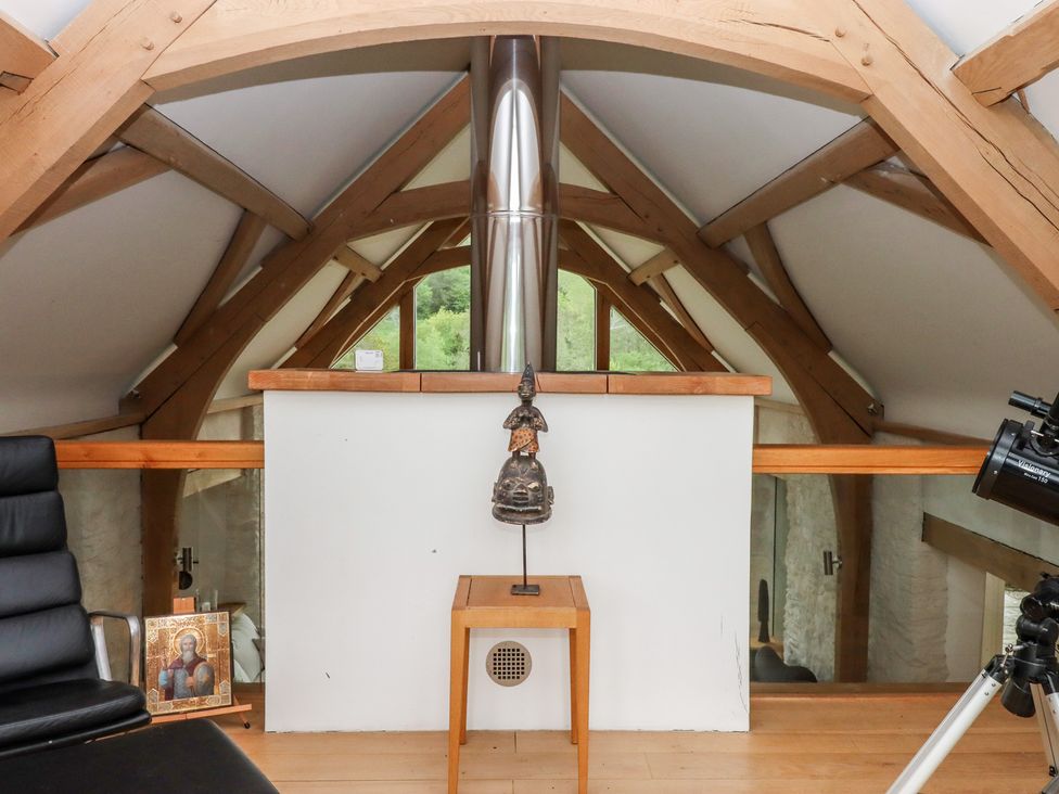 A loft with wooden beams and a decorative statue at Lower Velwell Barn in Totnes