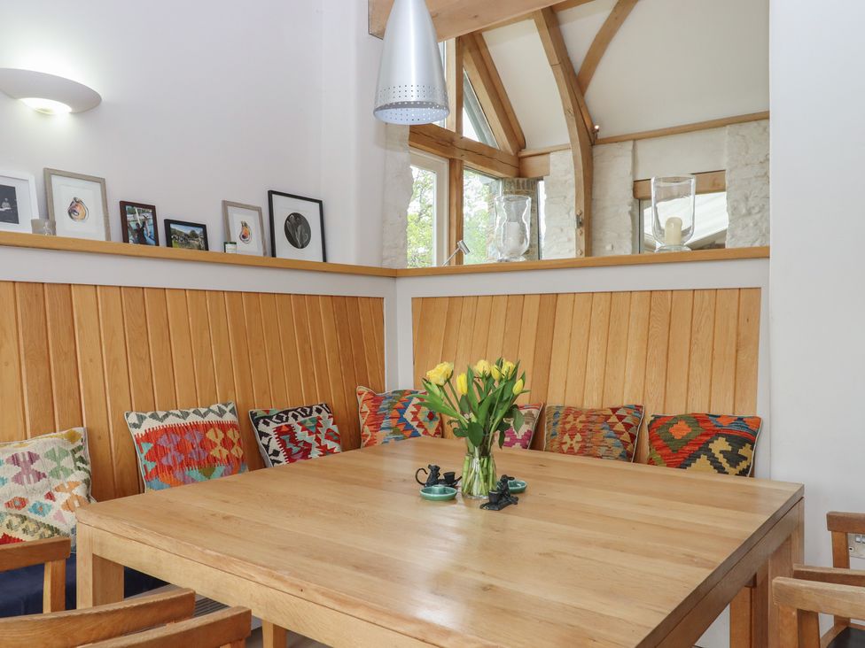 A dining room with a wooden table and chairs at Lower Velwell Barn in Totnes