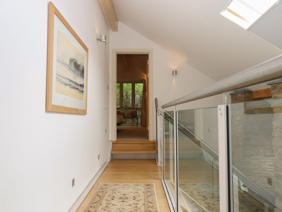A hallway with stairs and a painting at Lower Velwell Barn in Totnes