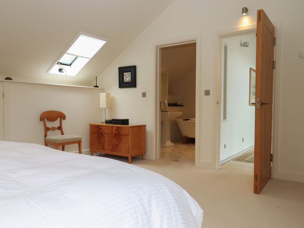 A bedroom with a bed and a chair at Lower Velwell Barn in Totnes