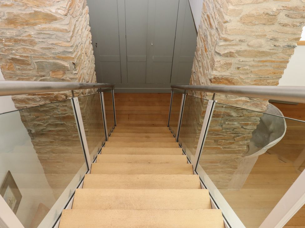 A staircase with wooden steps and glass railing at Lower Velwell Barn in Totnes