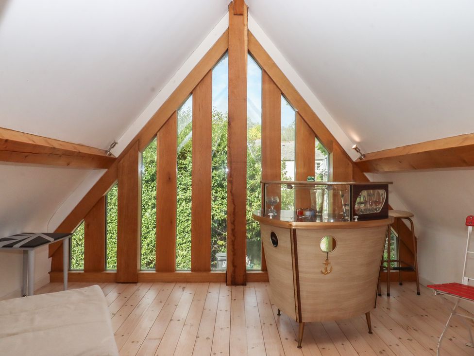 A loft with wooden beams and a bar at Lower Velwell Barn in Totnes