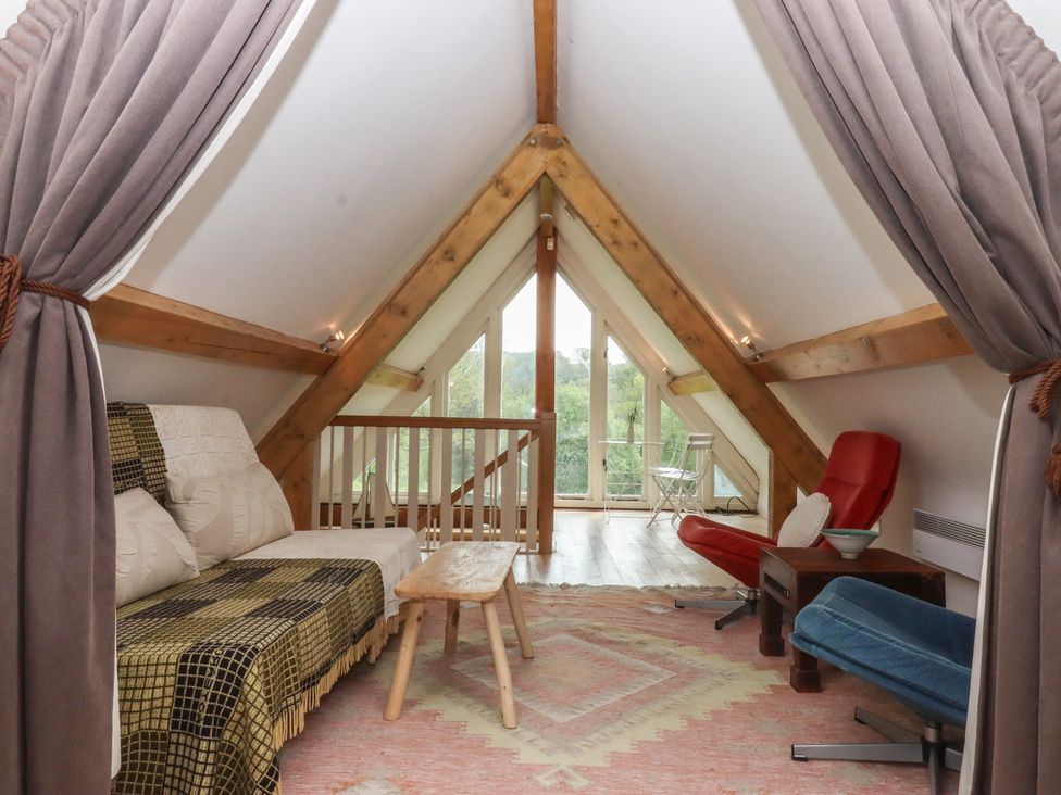 An attic with seating and a table at Lower Velwell Barn in Totnes
