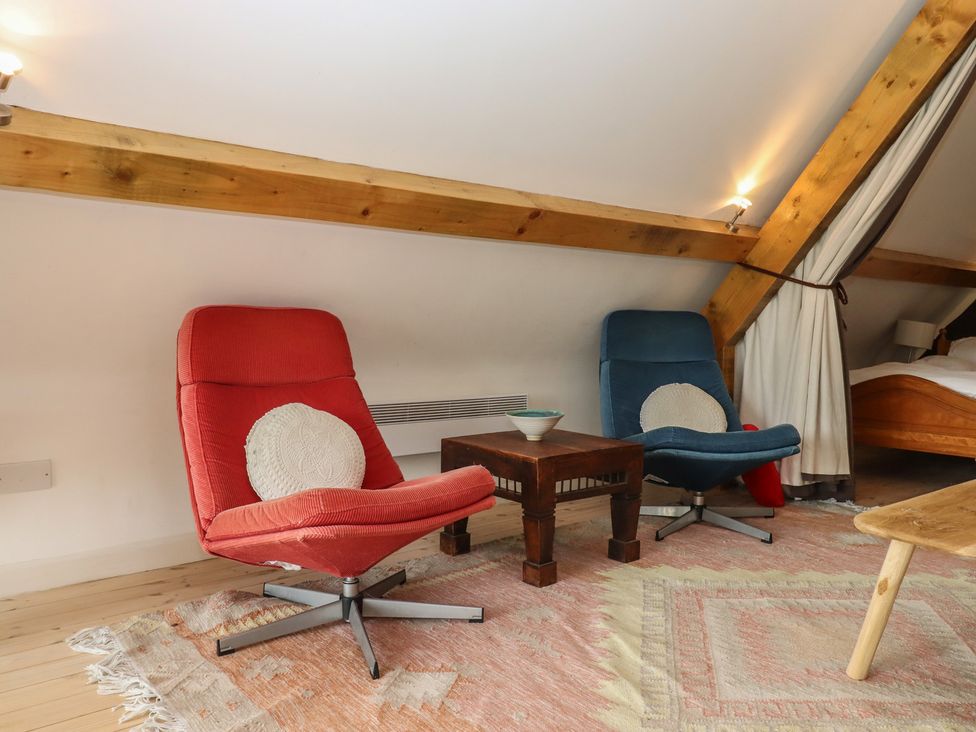 A living room with red and blue chairs and a coffee table at Lower Velwell Barn in Totnes