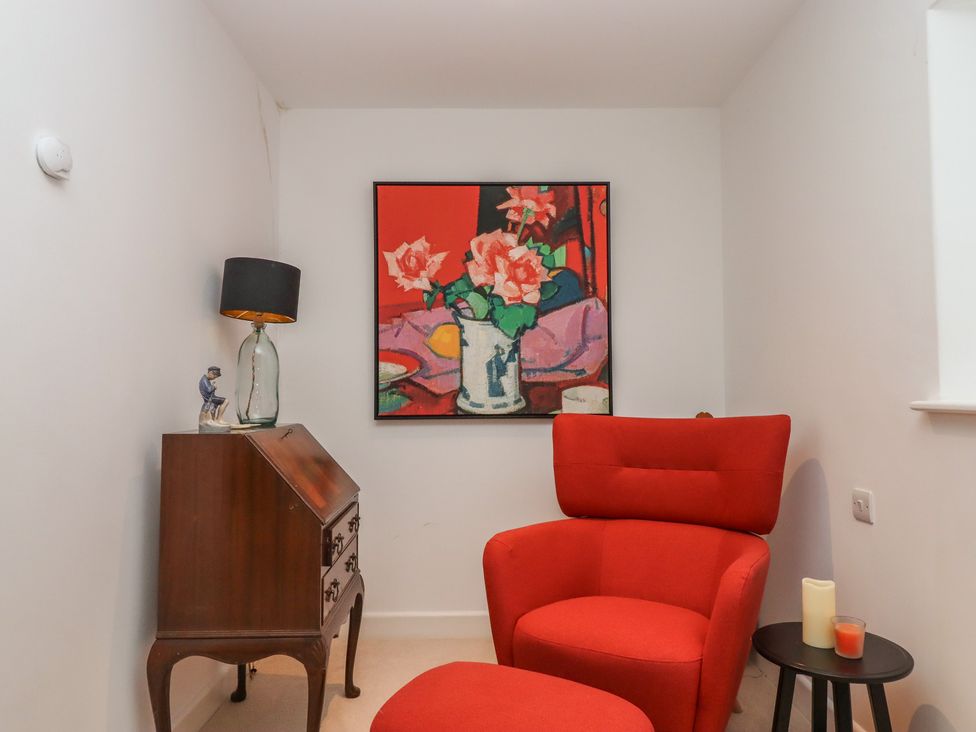 A snug with an armchair and a painting at Lower Velwell Barn in Totnes
