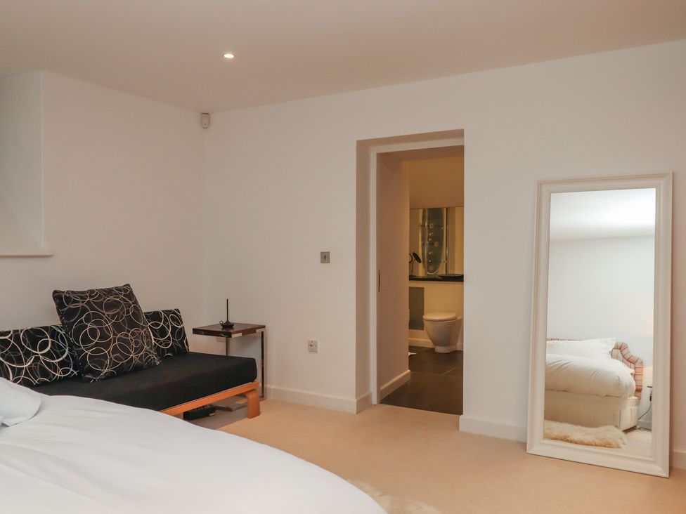 A bedroom with a bed and sofa at Lower Velwell Barn in Totnes