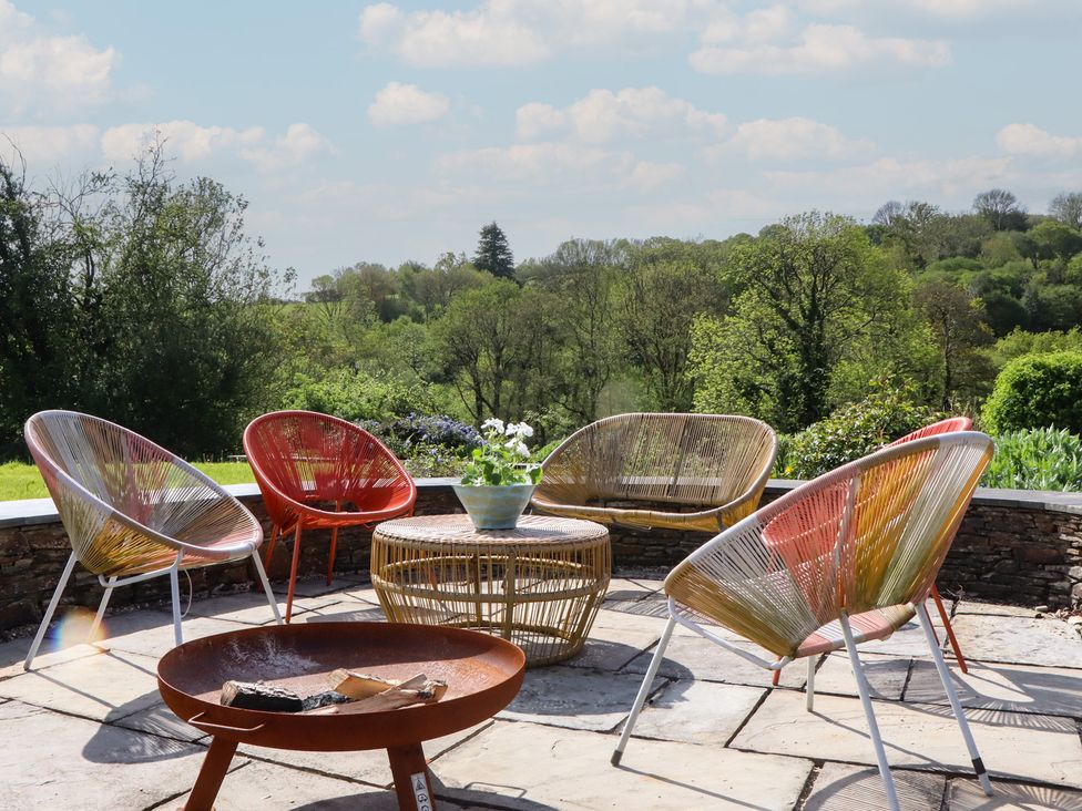 An outdoor seating area with chairs and a table at Lower Velwell Barn in Totnes