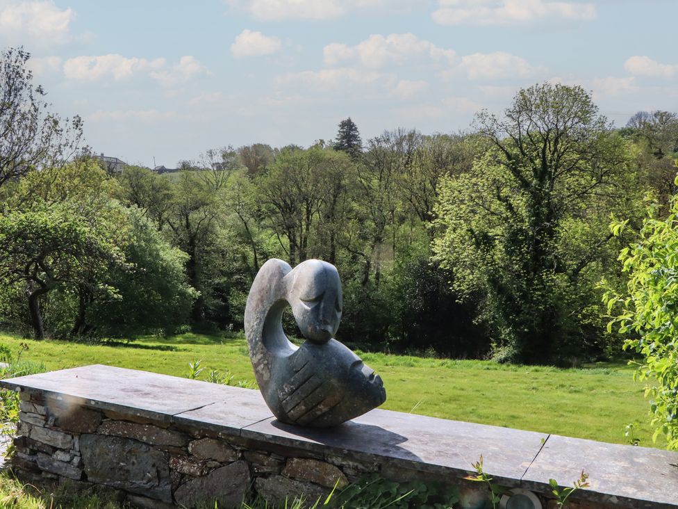 A sculpture on a stone bench overlooking a grassy area at Lower Velwell Barn, Totnes