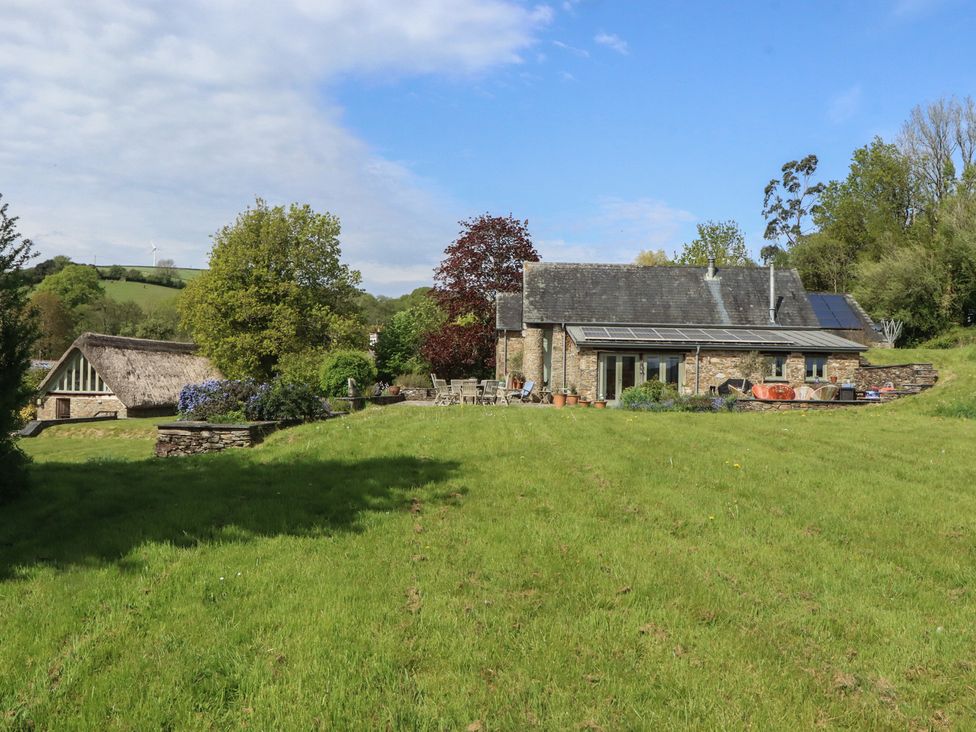 A house with solar panels and a barn in the garden at Lower Velwell Barn Totnes