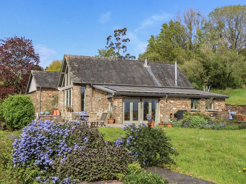A house with outdoor seating and flowers at Lower Velwell Barn Totnes