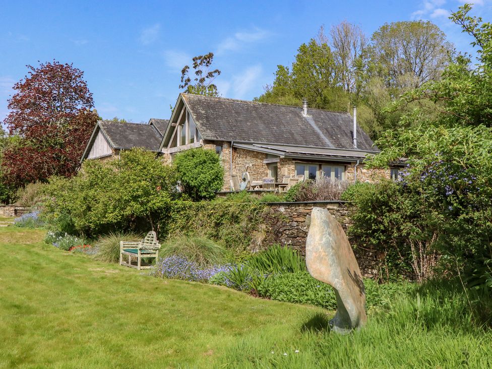 A house and garden with a stone sculpture at Lower Velwell Barn in Totnes