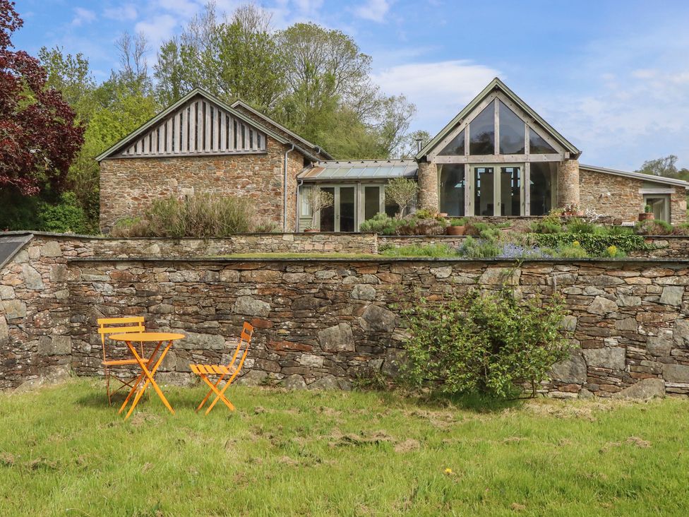 An outdoor area with a stone wall and an orange table at Lower Velwell Barn, Totnes