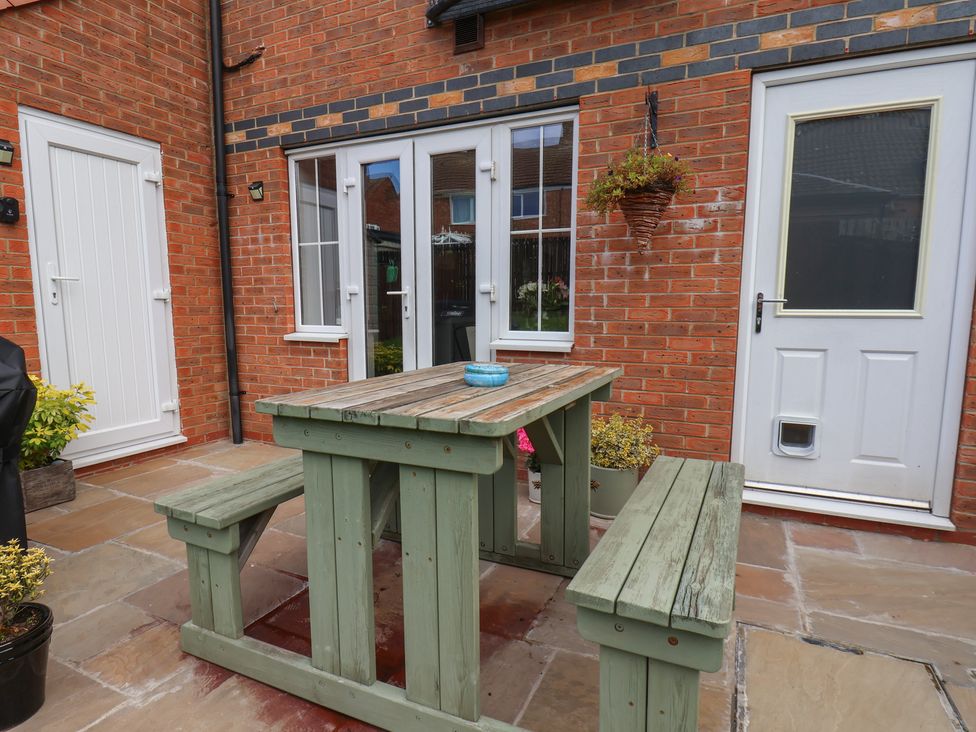 An outdoor seating area with a wooden table and benches at 33 Murrayfield Gardens, Whitby