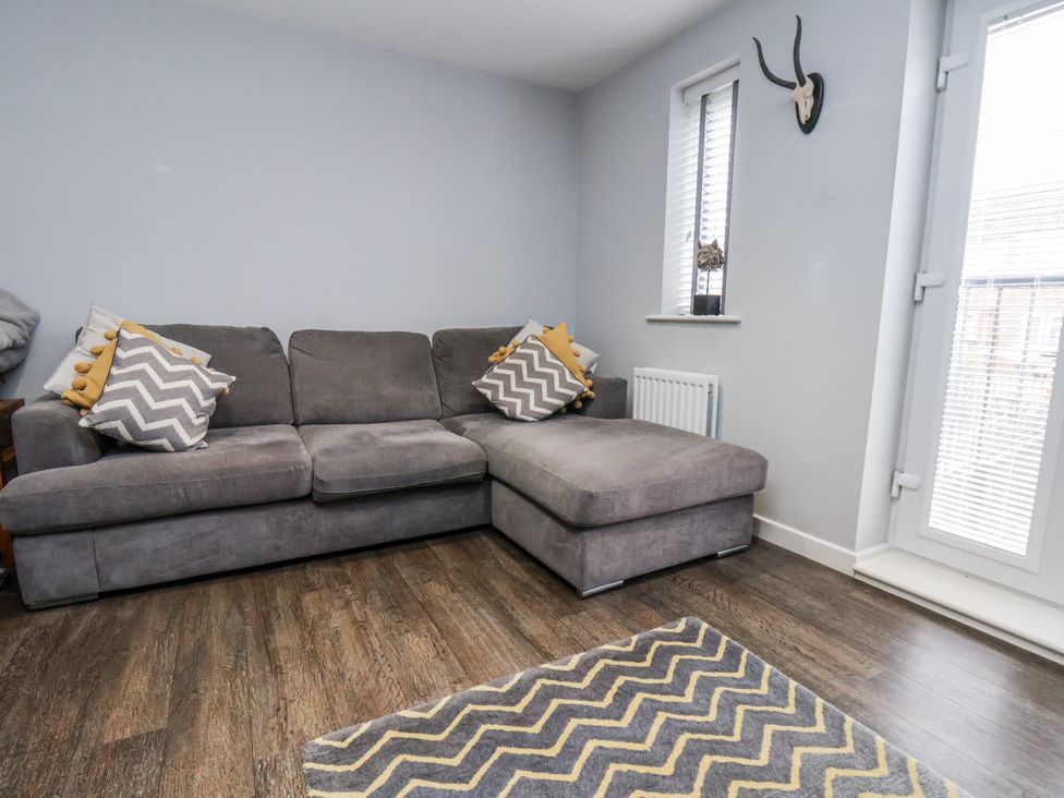 A living room with a grey sofa and cushions at Pearl Stone House in Whitby