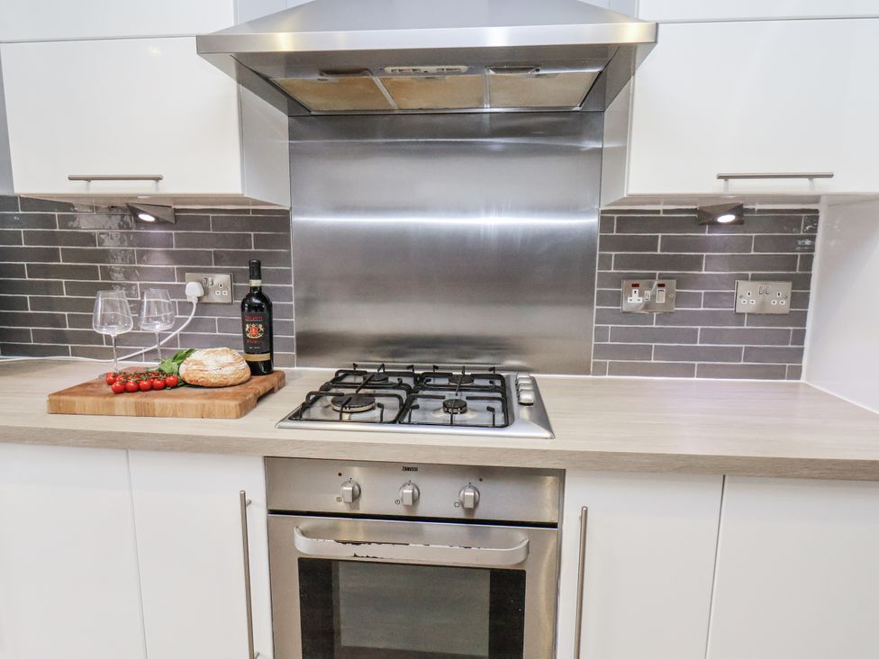A kitchen with a gas cooker and wine on the countertop at Pearl Stone House in Whitby