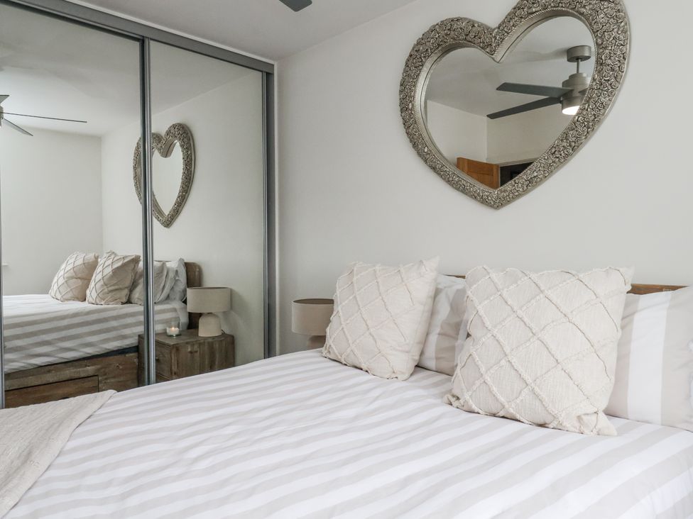 A bedroom with a bed, pillows, and a mirror at Pearl Stone House in Whitby