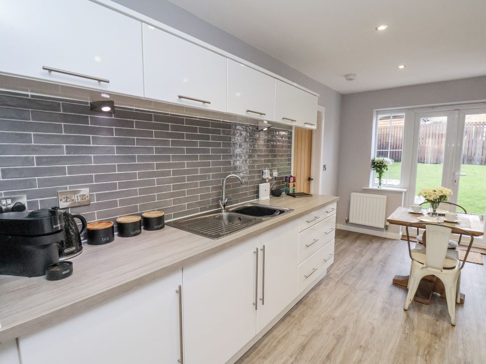 A kitchen with a countertop sink and dining area at Pearl Stone House in Whitby