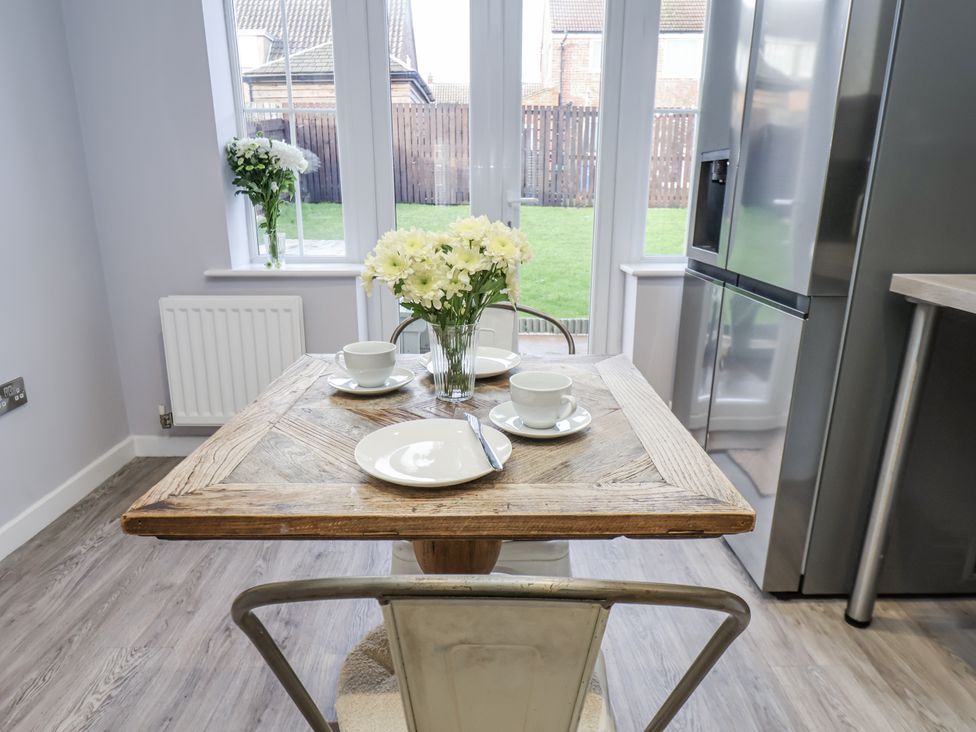 A kitchen with a wooden table set for two at Pearl Stone House in Whitby