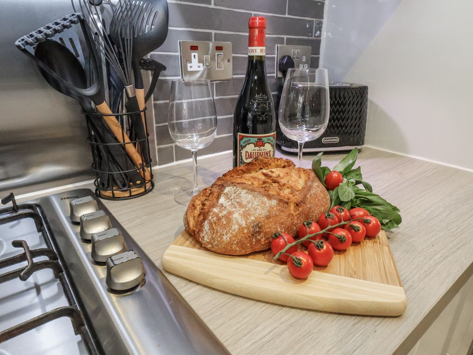 A kitchen counter with bread, tomatoes, wine, and glasses at Pearl Stone House, Whitby