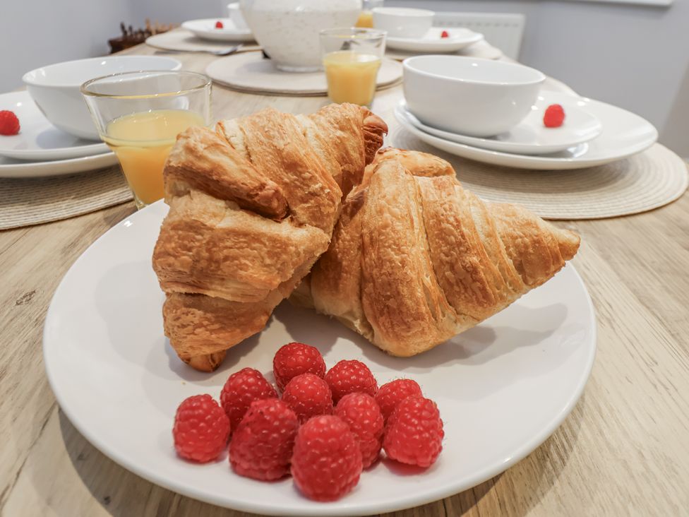 A plate with croissants and raspberries in a dining room at Pearl Stone House in Whitby