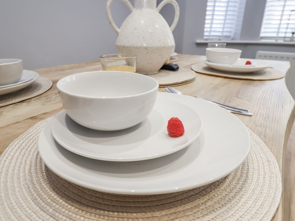 A dining table set with white plates and a pitcher at Pearl Stone House in Whitby