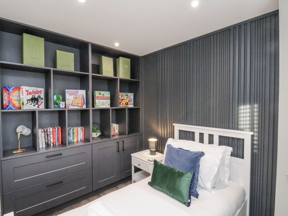 A bedroom with a bed and shelving containing books and games at Pearl Stone House in Whitby